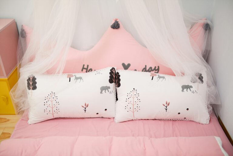 A charming children’s bed featuring pink decor, pillows with animal designs, and a canopy.